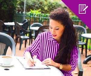A young woman sitting down having coffee and writing on a notebook
